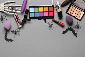 Different decorative cosmetics and Halloween decor on grey background