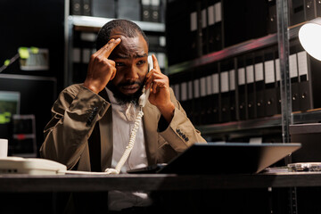 Worried detective discussing crime case insight with colleague on landline telephone. Stressed concerned investigator answering phone call to tell about investigation discovery