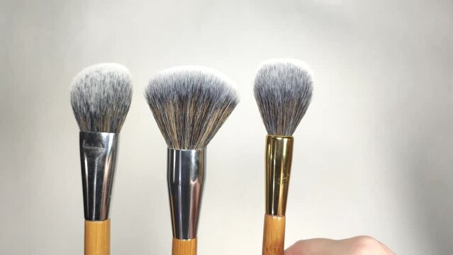 woman arranging makeup brushes with wooden handles in a row close-up