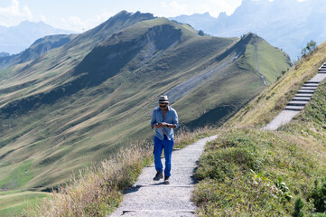 Fototapeta na wymiar Young man on an alpine hike in the Swiss mountains. He is photographing the beautiful landscape.