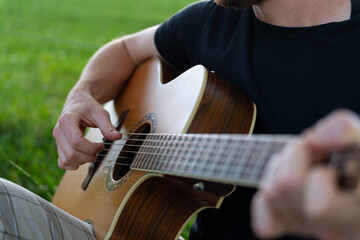 close-up hands of young guitarrist playing music outdoors