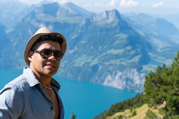 Naklejka premium Smiling young man on an alpine hike in the Swiss mountains. He enjoys the beautiful landscape. Alpin mountain panorama