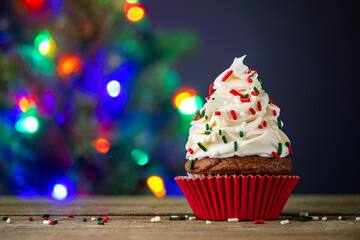 Cupcake. Cupcakes and Christmas Tree. Merry Christmas. Red cup liners. Tasty baking cupcakes, cake or muffin with white cream icing, frosting and colored sprinkles. Homemade bakery, confectionery shop