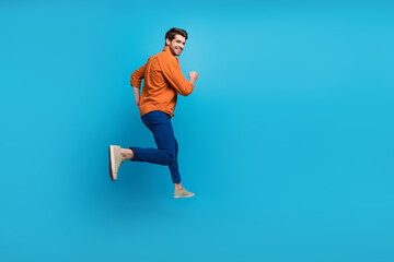 Fototapeta na wymiar Full length profile rear photo of overjoyed cheerful person jumping rush empty space isolated on blue color background