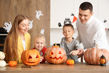 Happy family carving Halloween pumpkins in kitchen