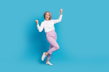 Fototapeta na wymiar Full body portrait of delighted aged lady raise fists achieve luck empty space isolated on blue color background