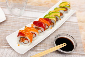 Fototapeta na wymiar Uramali roll served in sushi plate with soya sauce and other table appointments