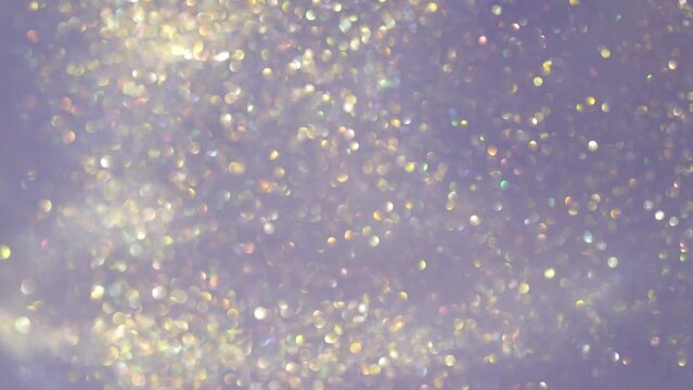 Shiny blurry particles floating in fluid. Abstract motion of silver sparkling sequins on light background. Amazing magic galaxy of flying defocused particles.