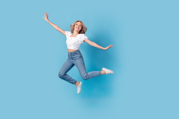 Fototapeta na wymiar Full length photo of sweet carefree lady wear white blouse jumping high flying empty space isolated blue color background
