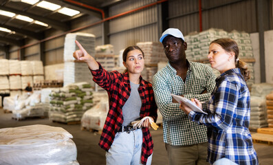 African-american man and caucasian women working in warehouse, talking about job. Employer and workers having conversation.