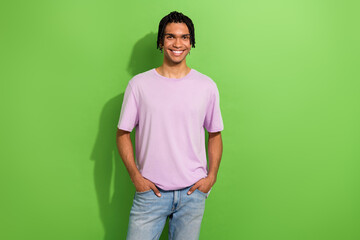 Photo of confident friendly person beaming smile put hands pockets posing empty space isolated on green color background