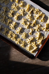 Shadowed lighting of uncooked pasta dough on a baking tray 