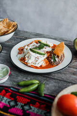 Mexican chilaquiles food with spicy red sauce, chicken and avocado traditional breakfast in Mexico Latin America