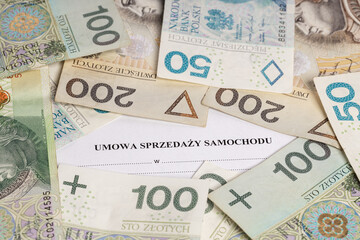 Fototapeta na wymiar Car sales contract, an inscription surrounded by Polish PLN banknotes (selective focus)