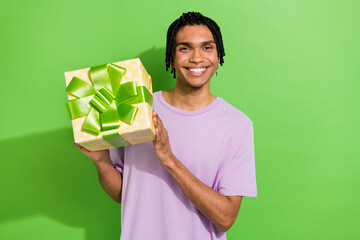 Portrait of funky friendly positive person beaming smile arms hold giftbox isolated on green color background