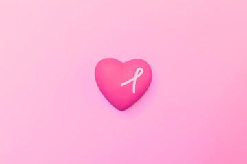Pink heart isolated on a pink background, adorned with a pink ribbon, symbolizing breast cancer awareness campaigns. Ideal for Pink October awareness month