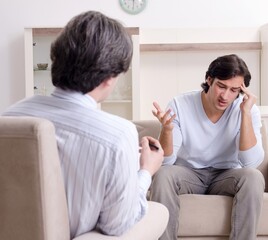 Fototapeta premium Young male patient discussing with psychologist personal problem