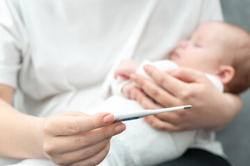 Obraz na płótnie Canvas Concerned mother checks for fever in her newborn. Concept of infant health vigilance