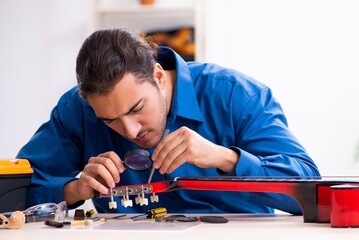 Young male repairman repairing guitar