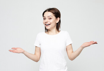 Young woman smiling, laughing, screaming, raising hands, opened mouth, over grey background