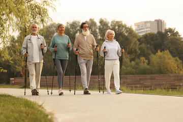 Group of senior people performing Nordic walking outdoors, space for text. Low angle view