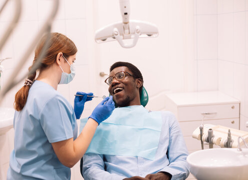 Portrait of black male patient getting teeth treatment with dentist.