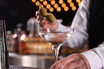 Bartender preparing fresh Martini cocktail at bar counter, closeup