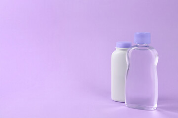 Bottles with baby oil and powder on violet background. Space for text