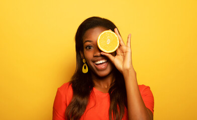 afro american woman hold orange slices look amazed isolated on yellow color background