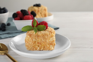 Piece of Napoleon cake with raspberries and spoon on wooden table, closeup