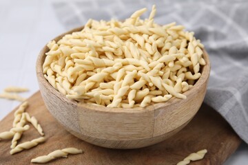 Bowl with uncooked Italian trofie pasta on table, closeup