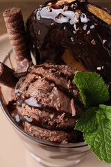 Delicious chocolate ice cream with wafer sticks, donut and mint in glass dessert bowl on table, above view