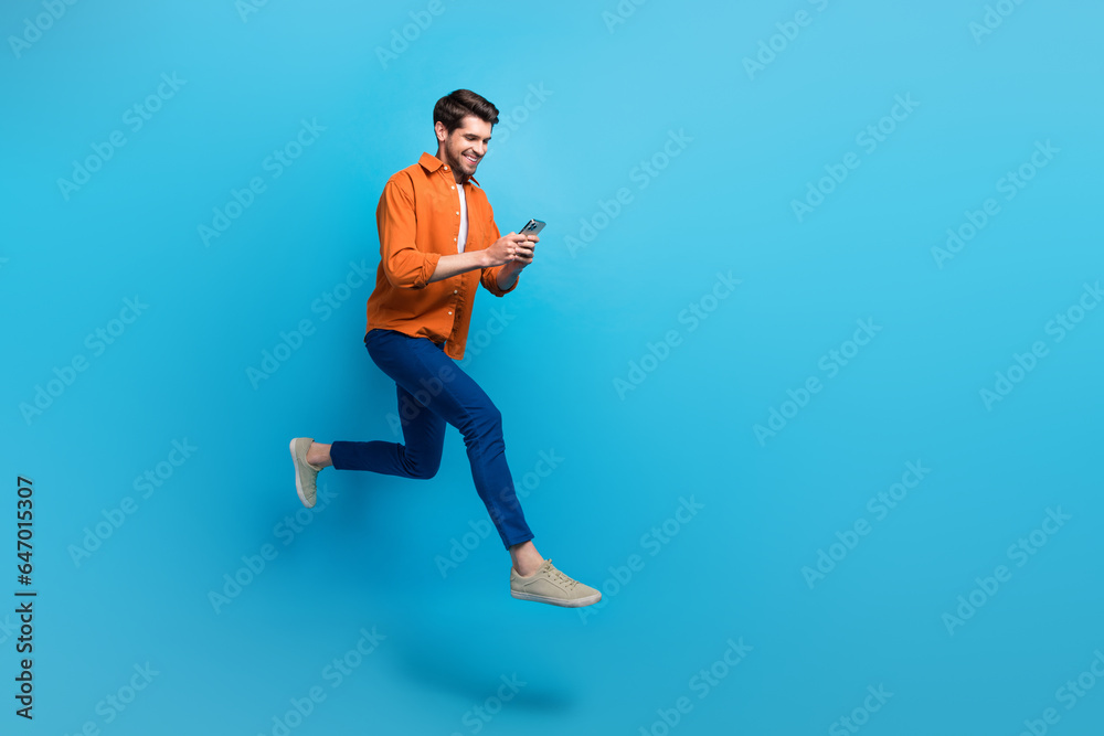 Aufkleber Full size profile photo of energetic attractive man use smart phone jumping run hurry empty space ad isolated on blue color background