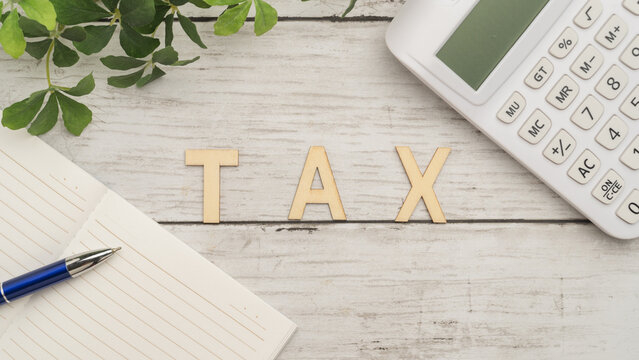 TAX(税金)イメージ｜白い木目背景とノートと電卓