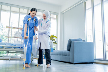 A Muslim Female doctor help a patient who is doing physical therapy and is practicing walking with a walking stick.
