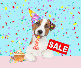 jack russell terrier puppy wearing party cap blows into party horn and showing signboard with labeled 