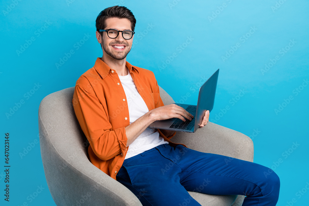 Poster Photo of attractive nice guy sitting comfort chair hold use wireless netbook networking isolated on blue color background