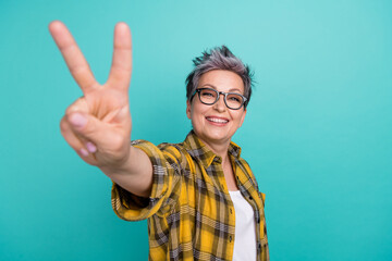 Photo of charming funny elderly lady showing v sign symbol peace gesture hippie oldschool isolated...