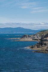 Fototapeta na wymiar Paisaje de bahía con acantilados recortados sobre el mar con cielo azul y nubes