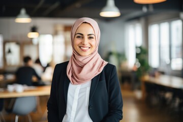 Smiling portrait of an arabic businesswoman wearing a hijab working in a startup company in a modern business office