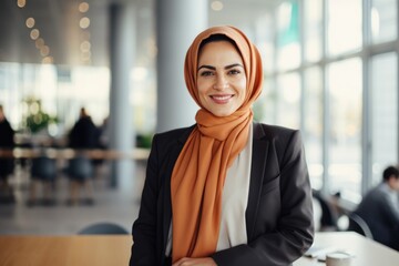 Smiling portrait of a businesswoman of arab descent wearing a hijab working in a startup company in a modern business office