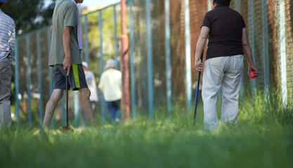 夏の朝の公園の運動場でグランドゴルフをやっている高齢者たちの姿