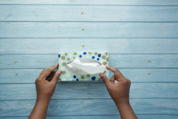  hand pull out a piece of tissue from tissue paper box 