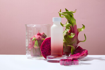 Advertising scene for cosmetic made from dragon fruit. A bottle with red dragon fruit slices on pink background. Dragon fruit can effectively treat acne and keep the skin from drying out