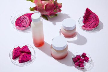 Minimal concept for advertising cosmetics with popular natural ingredients - red dragon fruit slices in a petri dishes with unlabeled bottle and jars on a white background