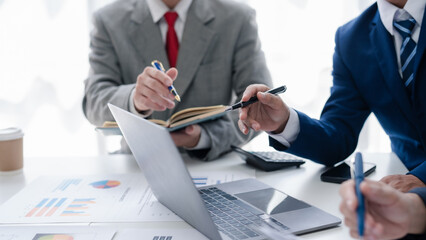 Business representatives meeting and planning graph presentation on laptop computer. Business team discussing investment plan using data on laptop.
