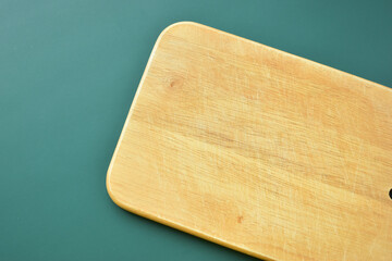 brown wooden cutting board on green background, equipment for cooking in the kitchen