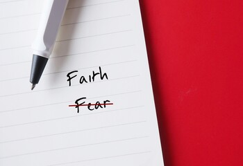 Pen writing on paper with text written FEAR crossed off to FAITH - concept of overcoming self doubt...