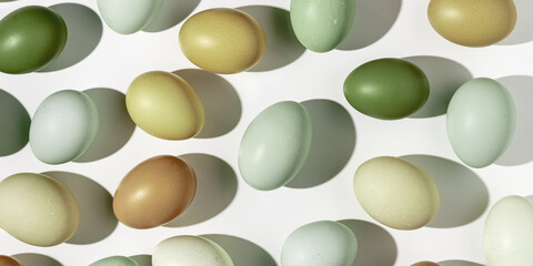 Easter eggs trend pattern, shadow at sunlight, white light background. Organic Chicken eggs with natural colored eggshells, food Easter celebration concept, top view, aesthetic flat lay, banner
