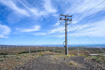 Power distribution lines on an industrial wind farm with wind turbines in the background, clean green energy
